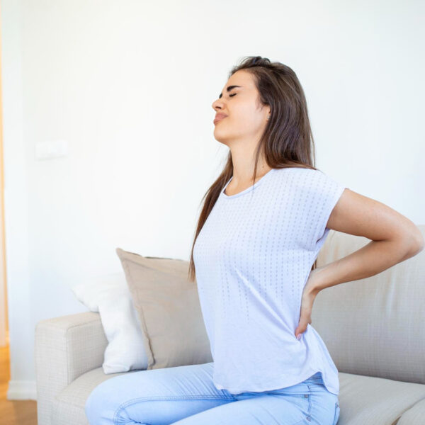 Woman suffering from backache at home Lower Back Pain Woman feels back pain massaging aching muscles sad woman suffers from lowback